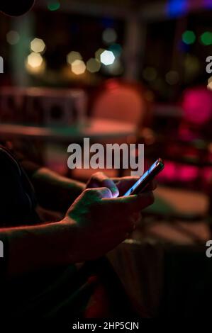 Mann, der im Club eine SMS an das Telefon schreibt Stockfoto