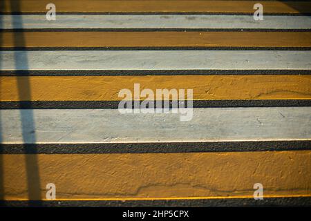 Fußgängerüberweg. Markierungen auf der Straße. Ort, um Straße zu überqueren. Gelbe und weiße Streifen. Stockfoto