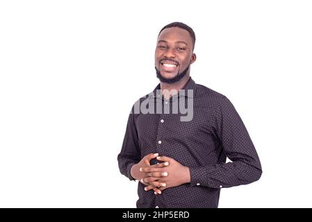 Porträt eines zufriedenen jungen, gutaussehenden Mannes, der seine Hände auf seinem Bauch hält und die Kamera anlächelt. Stockfoto
