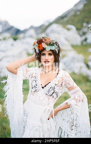 Braut im Kranz steht vor dem Hintergrund grauer Felsbrocken Stockfoto