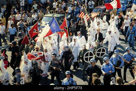 Austin, Texas, USA, um 1983: Eine kleine Gruppe von Ku Klux Klan-Mitgliedern, flankiert von der Polizei, zieht durch die Innenstadt von Austin, wo sie von einer feindlichen Anti-KKK-Menge getroffen werden. ©Bob Daemmrich Stockfoto