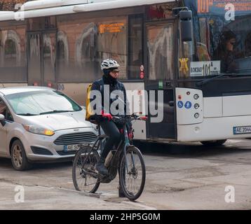 Dnepropetrovsk, Ukraine - 02.09.2022: Ein Lieferdienst-Kurier mit einem thermischen Beutel auf einem Fahrrad fährt um die Stadt. Lieferung von Lebensmitteln nach Hause. Stockfoto