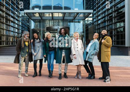 Diverse Kollegen lachen auf der Straße, bevor sie zusammenarbeiten Stockfoto