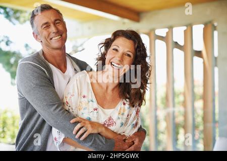 Sie teilen einen Sinn für Humor. Ein liebevoller reifer Mann umarmt seine Frau mit einem Lächeln. Stockfoto