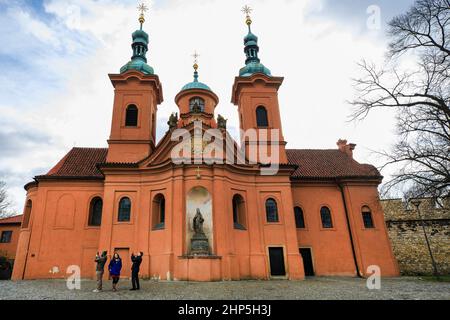 Touristen, die Fotos von der Kirche St. Vavrinec oder St. Lawrence mit orangefarbener Fassade und zwei grünen Kuppeln, Petrin Hill, Prag Tschechien Stockfoto