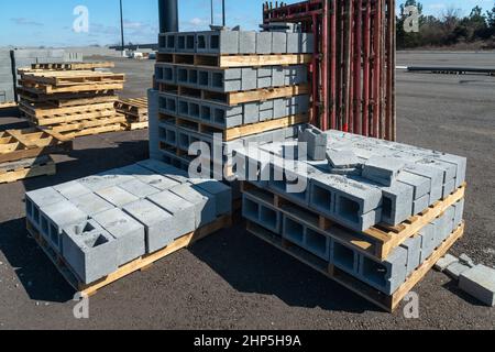 Horizontale Aufnahme von auf Holzpaletten gestapelten Zinkenblöcken an einer Baustelle. Stockfoto