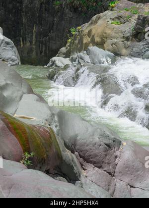 Foto zeigt felsige Schlucht, in der Gebirgsfluss fließt. Der Fluss fließt durch riesige Steinblöcke. Die bezaubernde Tierwelt der karibischen Insel begeistert Stockfoto