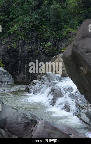 Foto zeigt eine felsige Schlucht, in der ein Gebirgsfluss fließt. Der Fluss fließt durch riesige Steinblöcke. Die bezaubernde Tierwelt der karibischen Insel begeistert Stockfoto