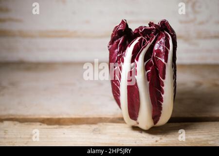 Radicchio Treviso oder italienische Zichorie, rotes Blattgemüse auf einem rustikalen Holztisch stehend, Kopierraum, ausgewählter Fokus, enge Schärfentiefe Stockfoto