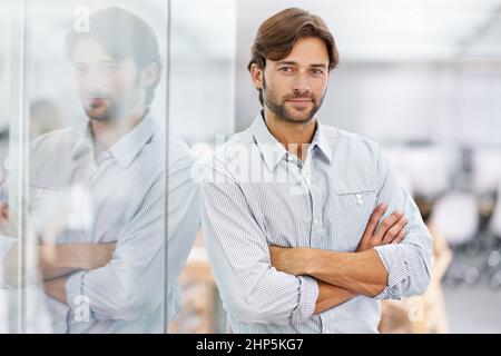HES ein selbstbewusster junger Geschäftsmann. Porträt eines hübschen jungen Geschäftsmannes, der in seinem Büro steht. Stockfoto