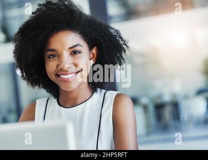 Unterschätzen Sie nicht ein hübsches Gesicht, sie geht ins Geschäft. Eine kurze Aufnahme einer attraktiven jungen Geschäftsfrau, die in ihrem Büro arbeitet. Stockfoto