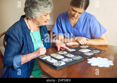 Shes hat viele Fotos zum Teilen. Aufnahme eines Wohnsitzes und einer Krankenschwester, die durch ein Fotoalbum schauen. Stockfoto