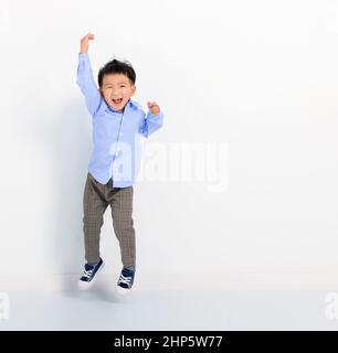 Glücklicher kleiner Junge, der auf weißem Hintergrund springt Stockfoto