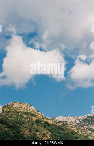 Weiße Wolken am blauen Himmel über den Gipfeln der Berge. Ansicht von unten Stockfoto