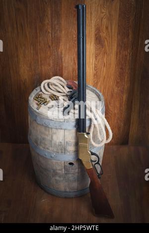 Old West Revolver und Gewehr mit Patronen auf Holzfass Stockfoto
