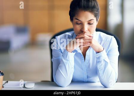 Den Druck spüren. Aufnahme einer jungen Geschäftsfrau, die gestresst aussieht, während sie an ihrem Schreibtisch sitzt. Stockfoto