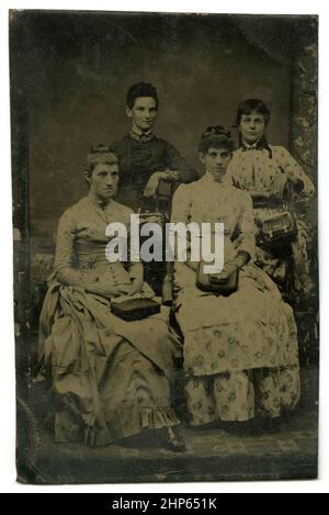 Antikes, um 1860 erzartes Foto, ein Studiobild von vier Frauen mit Taschenbüchern. Standort unbekannt, USA. QUELLE: ORIGINAL TINTYPE Stockfoto