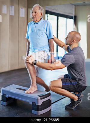 Der lange Weg zur Rehabilitation. Kurzer Schuss eines hübschen persönlichen Trainers mit einem älteren Mann. Stockfoto