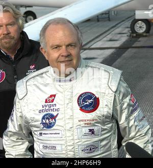 Pilot Steve Fossett spricht mit den Medien über den Grund, warum der Start des Virgin Atlantic GlobalFlyer verschoben wurde. Hinter Fossett steht Sir Richard Branson, Vorsitzender und Gründer von Virgin Atlantic. Hinter beiden steht das GlobalFlyer-Flugzeug Ca. 2006 Stockfoto