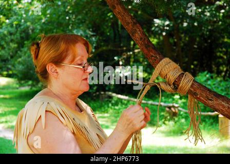 Eine Erwachsene Frau demonstriert das traditionelle Powhatan Handwerk der Seilherstellung Stockfoto