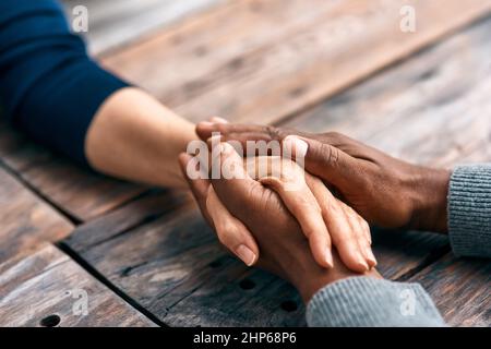 Ich finde Trost, wenn ich mit euch zusammen bin. Zugeschnittene Aufnahme von zwei nicht erkennbaren Personen, die sich die Hände hielten. Stockfoto