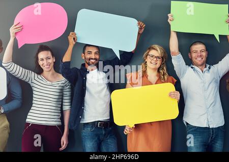 Nun, sei deine Stimme. Studioaufnahme einer vielfältigen Gruppe von Menschen, die Sprechblasen vor grauem Hintergrund halten. Stockfoto