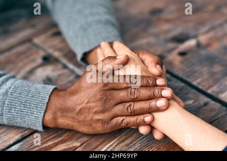 Ich bin hier, um Sie zu unterstützen. Zugeschnittene Aufnahme von zwei nicht erkennbaren Personen, die sich die Hände hielten. Stockfoto