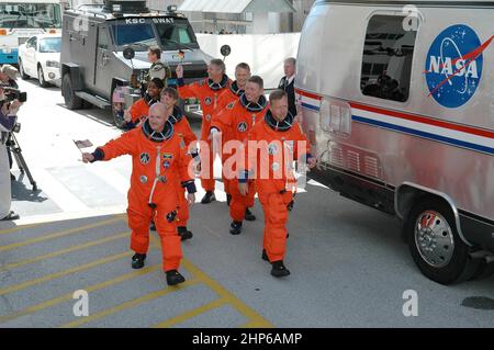 Die STS-121-Crew winkt am 4. Juli mit Flaggen und macht sich auf den Weg zum Astrovan und zum Ride to Launch Pad 39B für einen dritten Startversuch. An der Spitze stehen Pilot Mark Kelly (links) und Commander Steven Lindsey (rechts). Dahinter stehen links und rechts die Missionsspezialisten (zweite Reihe) Lisa Nowak und Michael Fossum, (dritte Reihe) Stephanie Wilson und Piers Sellers und (hinten) Thomas Reiter, der die Europäische Weltraumorganisation vertritt Stockfoto