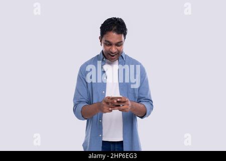 Indischer Mann Steht Mit Telefon Über Überschritten Isoliert. Man Texting on Phone. Technologie Stockfoto