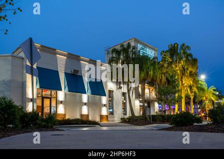 Kissimmee, Florida - 6. Februar 2022: Nachts Nahaufnahme Blick auf das Estefan Kitchen Restaurant Gebäude außen mit beleuchteten Palmen rundherum. Stockfoto