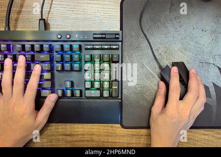 Nahaufnahme der Gamer, die mechanische Gaming-Tastatur und Gaming-Maus für Spiele auf Computer-PC-Desktop auf Draufsicht, E-Sport Stockfoto