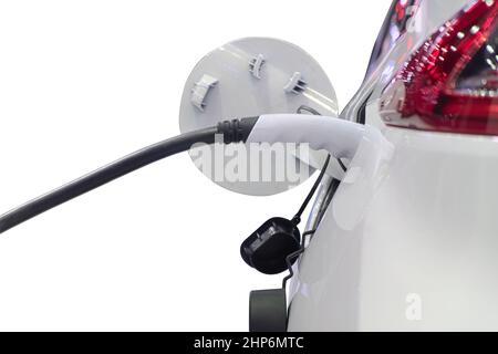 Nahaufnahme des elektrischen Ladegerätes, der mit einem Stecker zum Laden der Batterie auf einem weißen Elektroauto verbunden ist, isoliert auf weißem Hintergrund Stockfoto