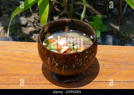 Soto Batok, eine javanesische Rindfleischsuppe mit Gemüse und Reis, serviert in einer traditionellen Schüssel aus Kokosnussschale Stockfoto