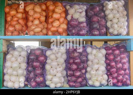 Zwiebeln in Netzen zum Verkauf. Verschiedene rote, weiße und gelbe Glühbirnen. Stockfoto