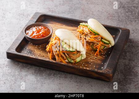 Gedämpfte bao-Sandwiches mit gezogen Schweinefleisch und Gemüse Nahaufnahme auf einem Holztablett auf dem Tisch. Horizontal Stockfoto