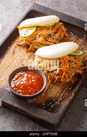 Gedämpftes bao-Brötchen gefüllt mit Pulled Schweinefleisch und Gemüse köstliche Gourmet-Snack in der Nähe in der Holzbrett auf dem Tisch. Vertikal Stockfoto