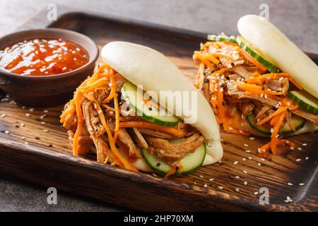 Köstliche gedämpfte bao-Brötchen-Sandwiches mit gezogenem Schweinefleisch aus nächster Nähe auf einem Holztablett auf dem Tisch. Horizontal Stockfoto