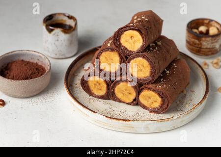 Vegane Schokolade dünne Crepes mit Banane auf Keramikplatte Stockfoto