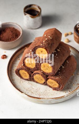 Gerollte vegane Schokoladencrepes mit Bananen und Nüssen Stockfoto