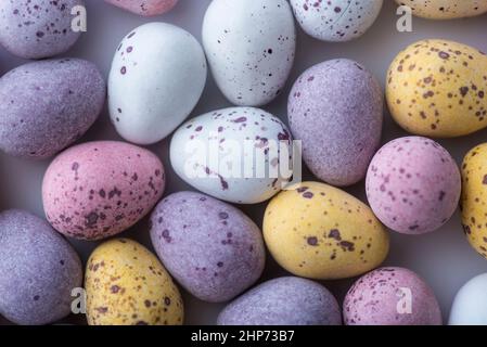 Bunte gesprenkelte Mini-Ostereier auf einem schlichten Boden von oben geschossen, flach liegend Stockfoto