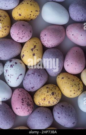 Bunte gesprenkelte Mini-Ostereier auf einem schlichten Boden von oben geschossen, flach liegend Stockfoto