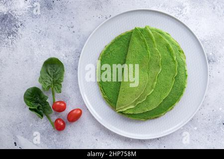 Grüne Spinat-Pfannkuchen, Crepes auf blauem Teller. Veganes Essen Stockfoto