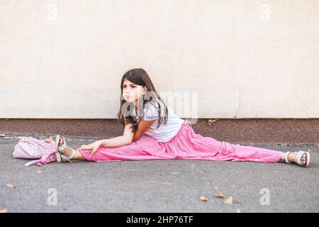 Kleine Brünette Mädchen beiläufig tun Split im Freien Stockfoto