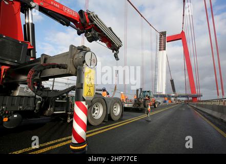 Emmerich, Deutschland. 19th. Februar 2022. Bauarbeiter bauen Gerüste auf der Emmerich-Rheinbrücke ab. Sturm Zeynep hatte Teile des Gerüsts auf die Straße geschoben. Der Verkehr über den Rhein ist bis auf weiteres gesperrt. Quelle: Roland Weihrauch/dpa/Alamy Live News Stockfoto