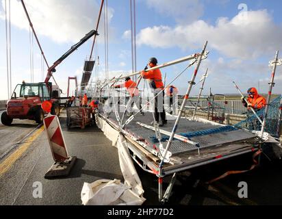 Emmerich, Deutschland. 19th. Februar 2022. Bauarbeiter bauen Gerüste auf der Emmerich-Rheinbrücke ab. Sturm Zeynep hatte Teile des Gerüsts auf die Straße geschoben. Der Verkehr über den Rhein ist bis auf weiteres gesperrt. Quelle: Roland Weihrauch/dpa/Alamy Live News Stockfoto