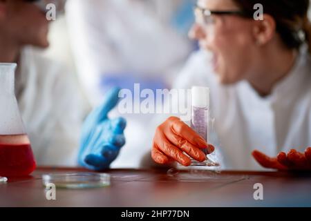 Junge Chemiestudenten in Schutzkleidung experimentieren gerne in einer Arbeitsatmosphäre im Universitätslabor mit gefährlichen Chemikalien. Wissenschaft, Stockfoto