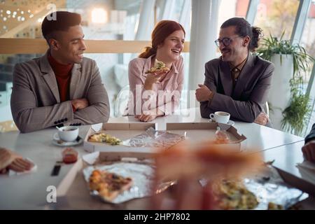 Eine junge Geschäftsfrau macht sich mit ihren männlichen Kollegen während einer Mittagspause in freundlicher Atmosphäre im Firmengebäude Spaß. Unternehmen, Mitarbeiter, Stockfoto
