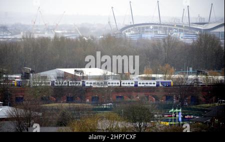 Manchester, Großbritannien, 19th. Februar 2022. Ein Zug fährt von der Piccadilly Station, Manchester, Großbritannien, ab. Die Züge werden nach dem Sturm Eunice von Manchester, England, Großbritannien und den Britischen Inseln abgesagt und verzögert. Es gibt keine Züge von Manchester nach Preston, wo der Sturm Eunice das Dach des Bahnhofs beschädigt hat. Die Mitarbeiter von Network Rail überprüfen die Bahnlinien auf umgestürzte Bäume und Schäden. Der öffentliche Nahverkehr in ganz Europa ist von dem Sturm betroffen. Etihad Stadium im Hintergrund. Quelle: Terry Waller/Alamy Live News Stockfoto