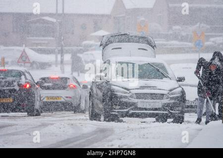 Schnee und Eis verursachen Störungen auf den Hügeln um Bradford, West Yorkshire, Großbritannien. 19.. Februar 2022. Autos haben Schwierigkeiten, sich auf rutschigen Winterböden zu bewegen. Frauen versuchen, auf verschneiten Hügeln Räder zu räumen, um ihr Auto in Bewegung zu bringen. Stockfoto