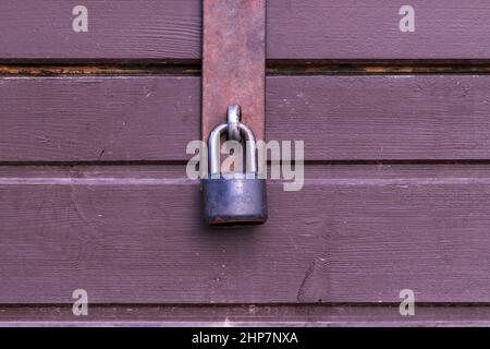 Schwarzes Vorhängeschloss an der Tür eines Holzständers. Verriegelten Fenster mit einem Vorhängeschloss. Stockfoto